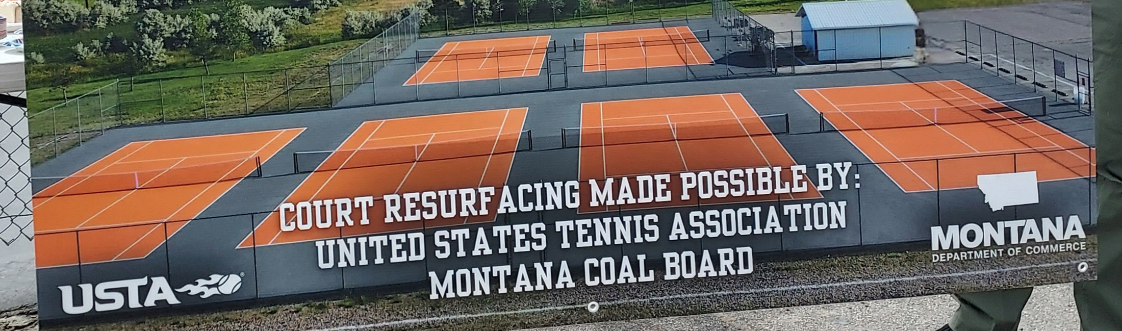 Attendees display signage at a ribbon-cutting ceremony for Hardin’s new tennis courts, funded in part by a grant from the Montana Coal Board. Photo credit: Commerce.